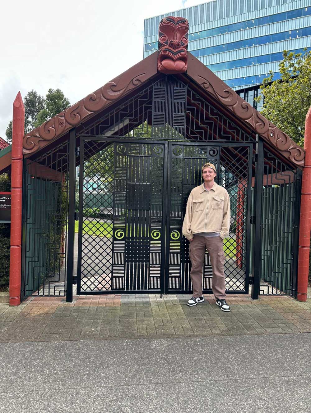 Daniel Hoare standing in front of traditional Māori architecture in Auckland, New Zealand.