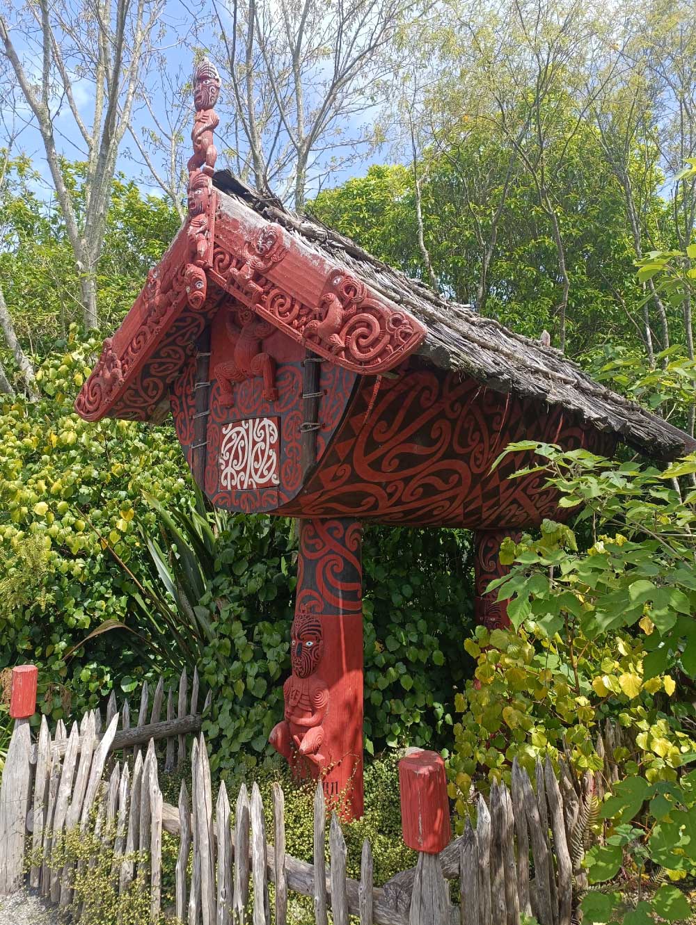 Close-up of a Māori food storage building featuring intricate wood carvings and hand-painted pattern designs.